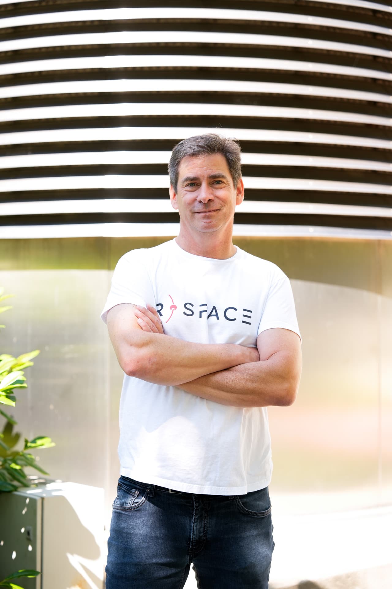 Person wearing an R-Space T-shirt standing next to a whiteboard with handwritten notes in a modern office setting.