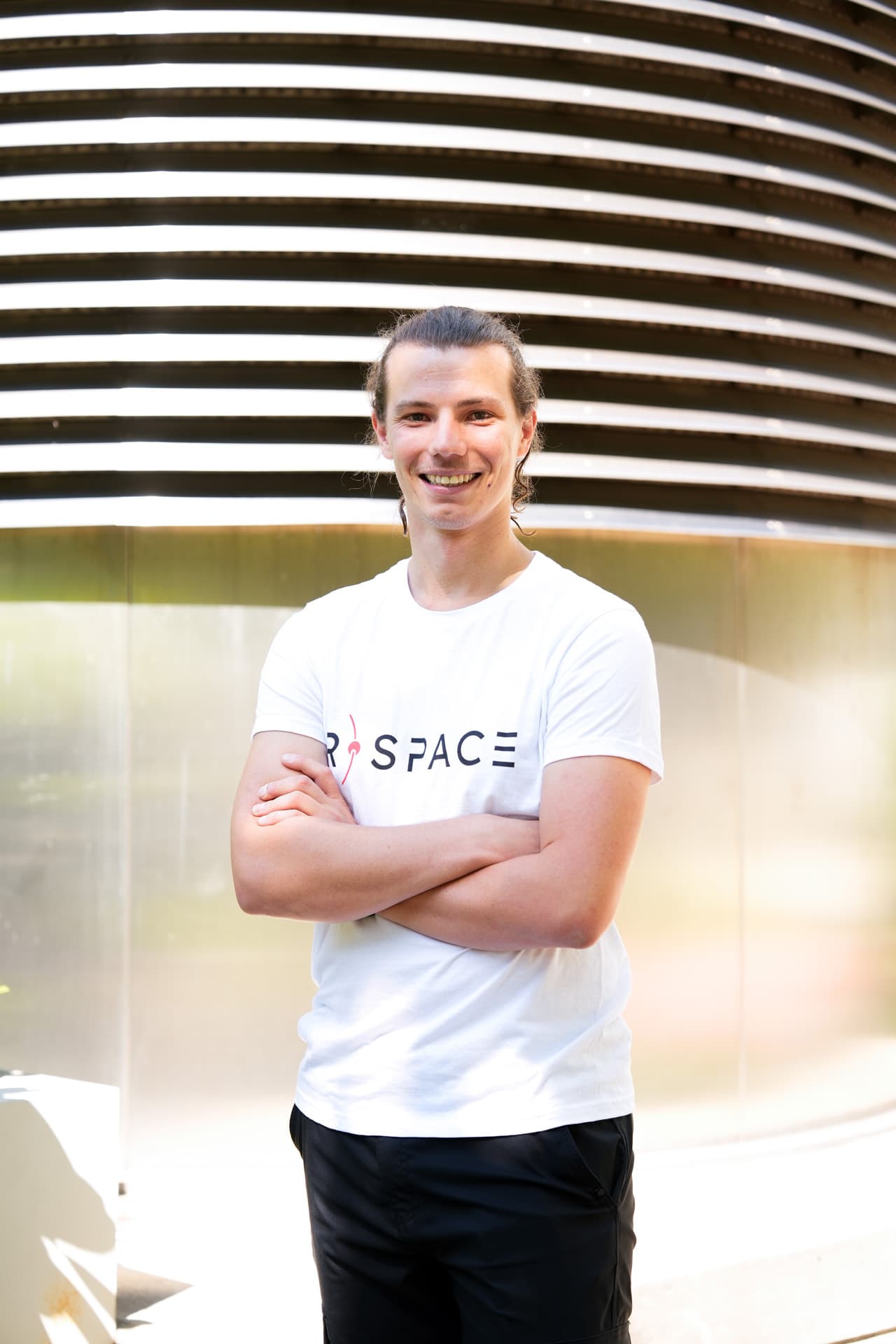 Person wearing an R-Space T-shirt standing next to a whiteboard with handwritten notes in a modern office setting.