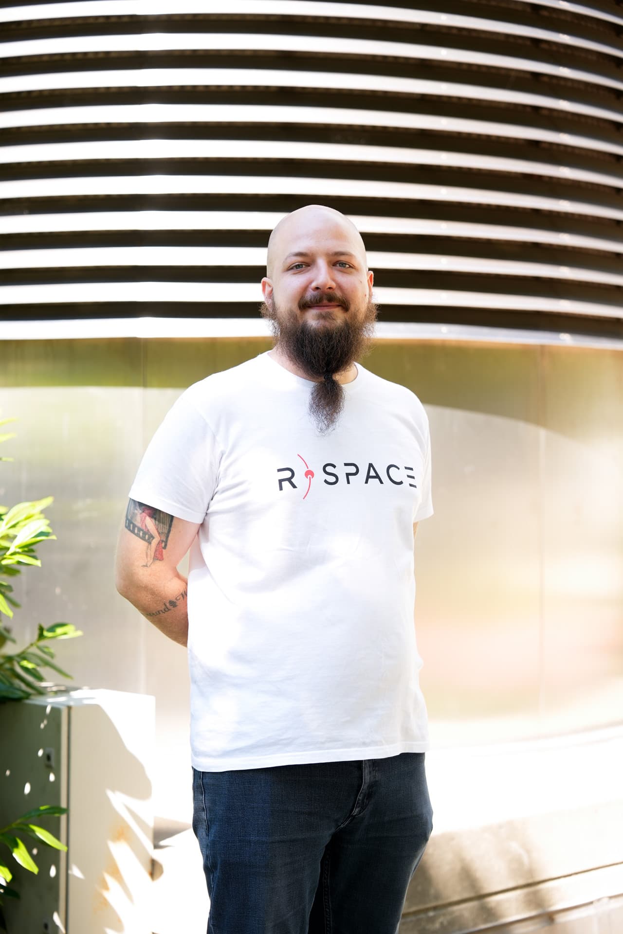 Person wearing an R-Space T-shirt standing next to a whiteboard with handwritten notes in a modern office setting.
