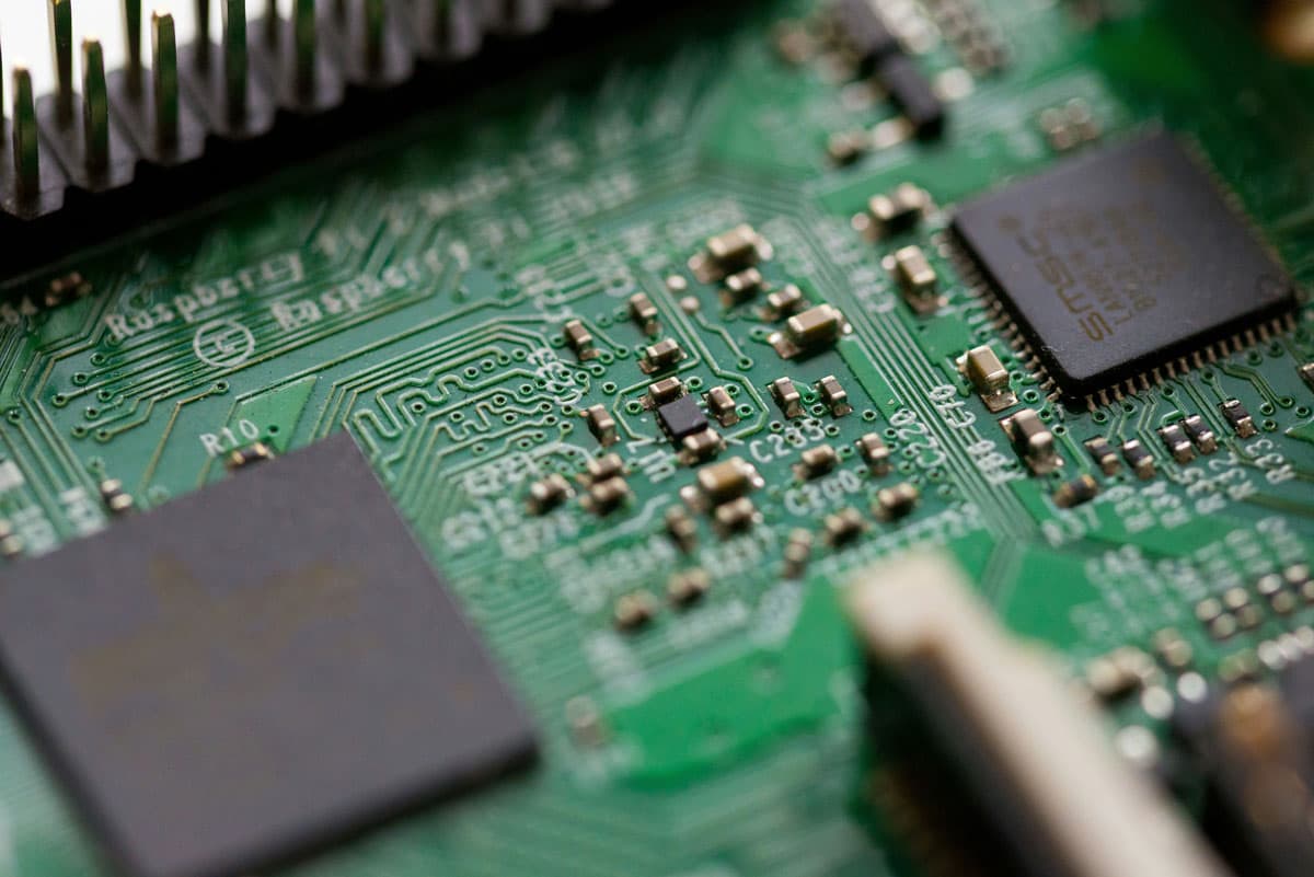 Close-up of a green printed circuit board (PCB) with microchips, resistors, and electronic components