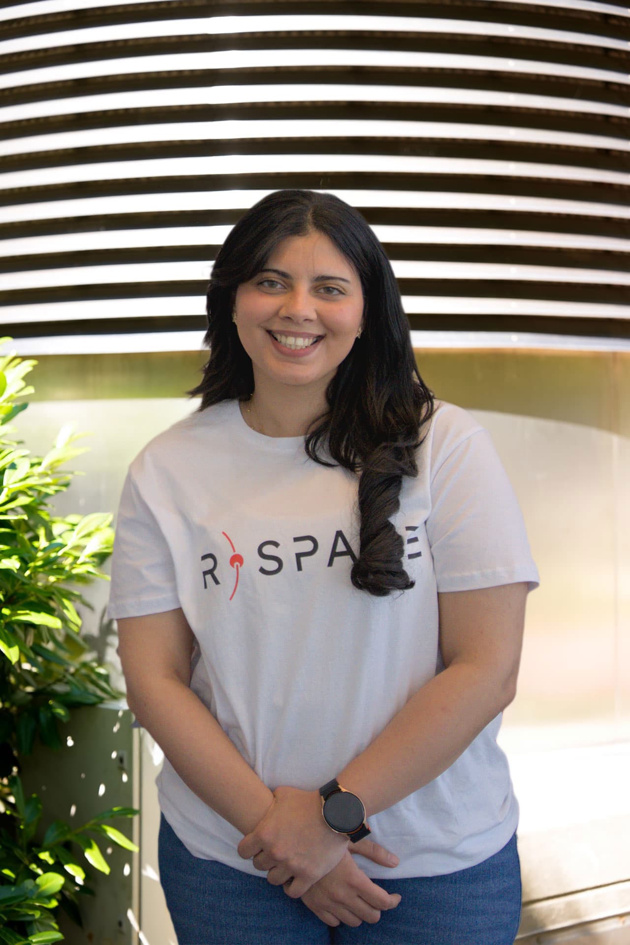 Person wearing an R-Space T-shirt standing next to a whiteboard with handwritten notes in a modern office setting.
